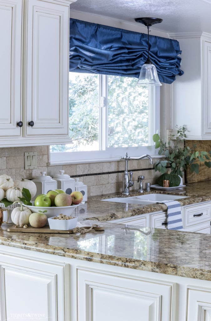 french kitchen with partial overlay cabinet doors and blue curtain above window