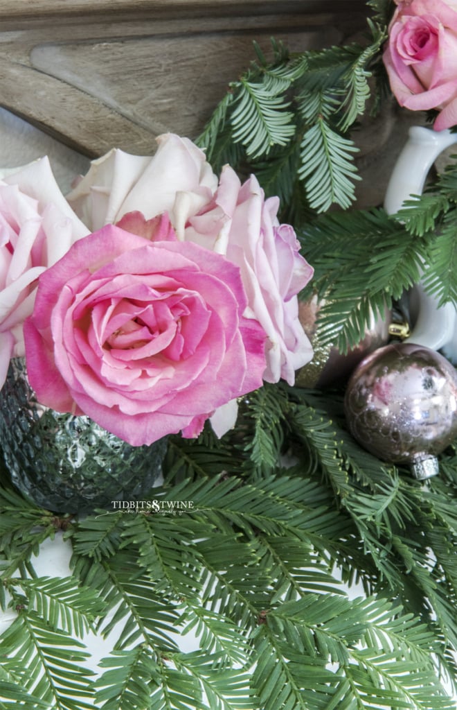 Pink rose in mercury vase with greenery and ornament on fireplace mantel