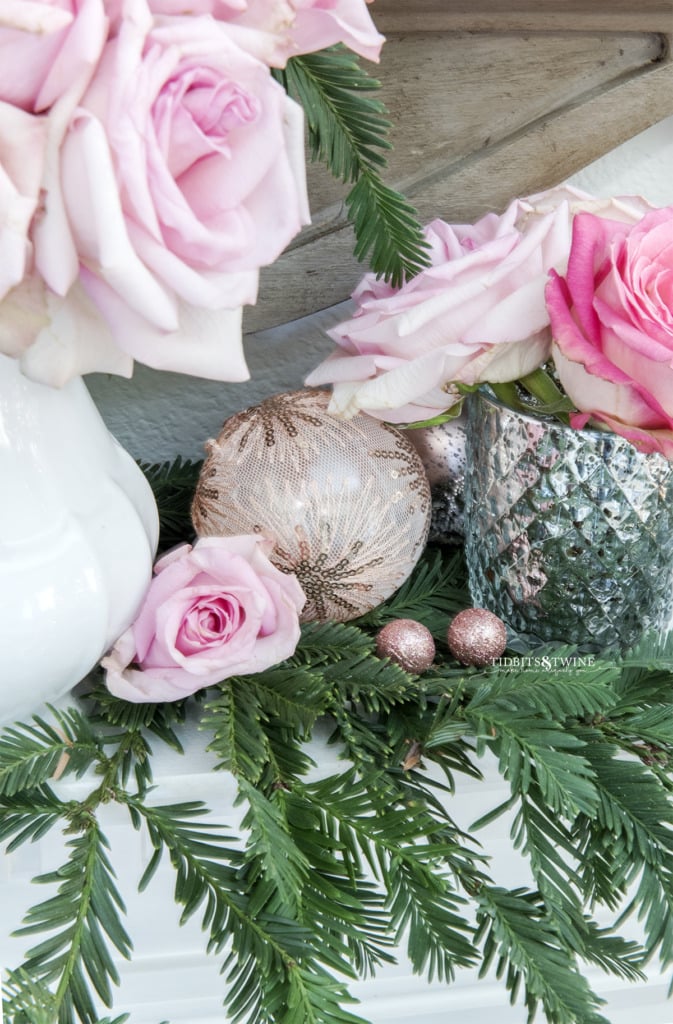 Pink Christmas ornaments with roses and greenery on a fireplace mantel