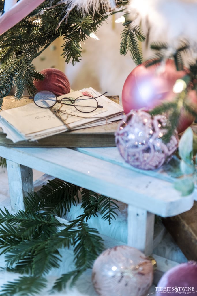 Wood sled underneath a Christmas tree with pink ornaments and vintage books