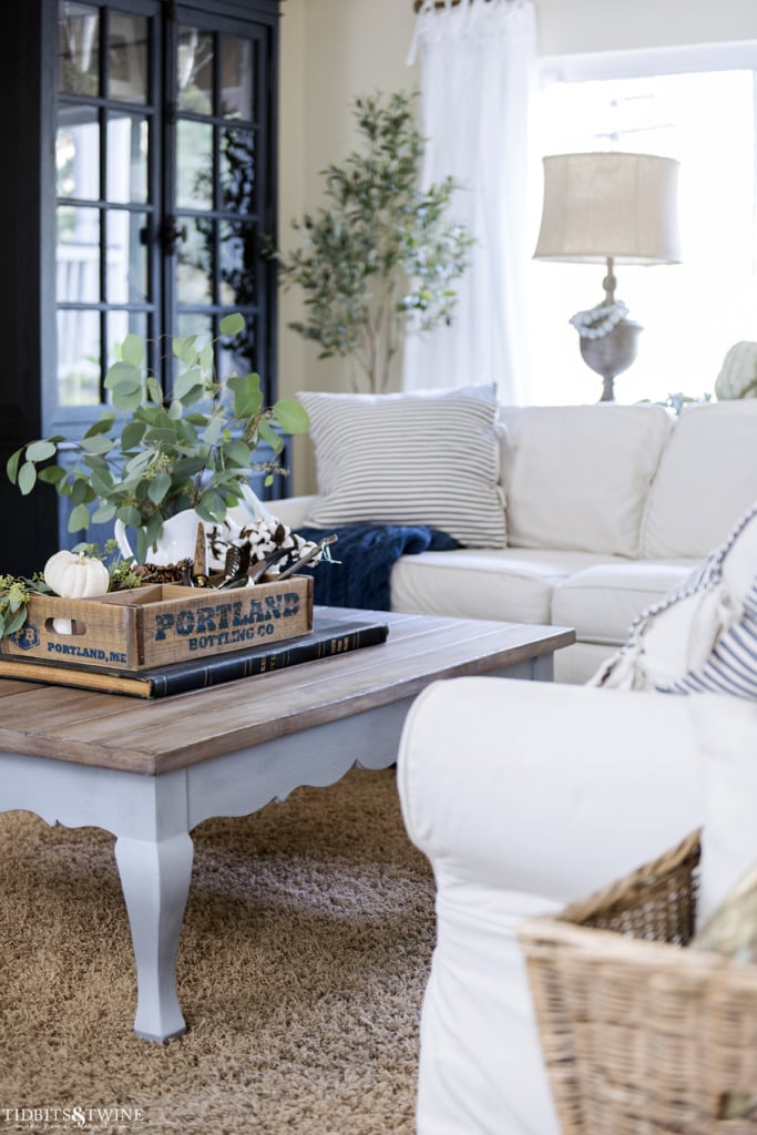 French coffee table with fall decor on top in family room with white pottery barn sectional sofa