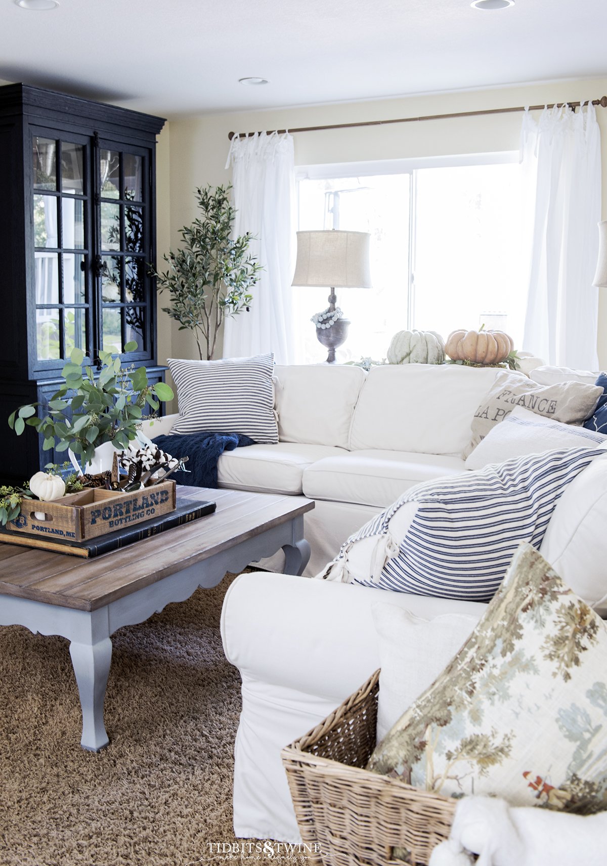 A French family room with a white Pottery Barn slipcovered sofa and French coffee table and black cabinet for Fall