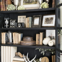 black french cabinet decorated for fall with antique books trophies and dried hydrangea