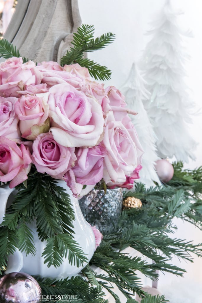 Pink roses with white ironstone and Christmas greens on fireplace mantel