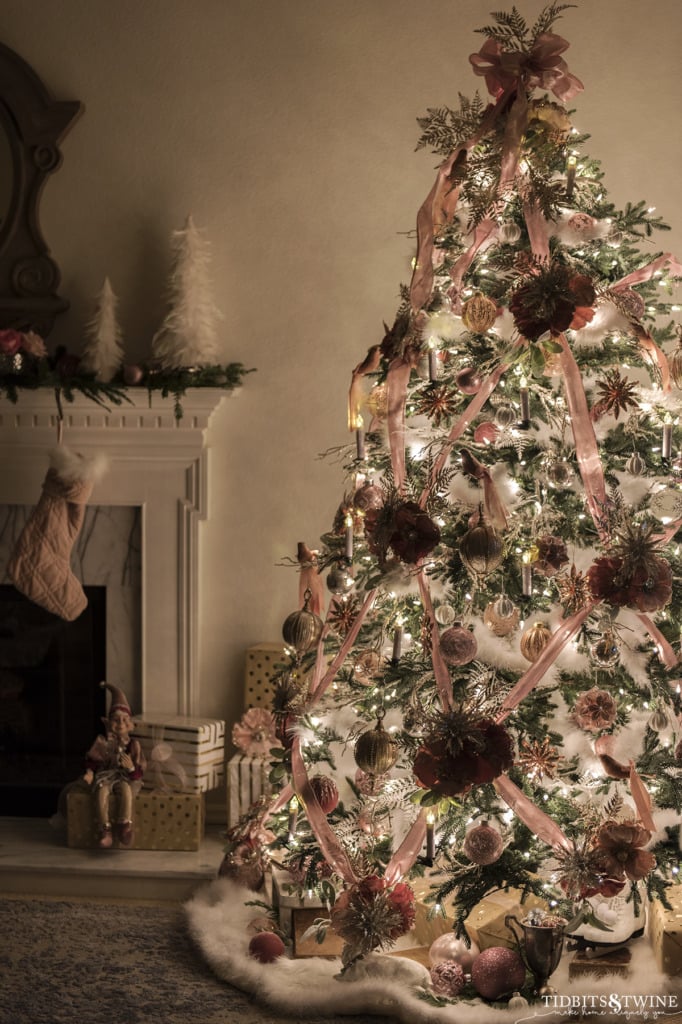 Pink and white decorated Christmas tree at night in French living room