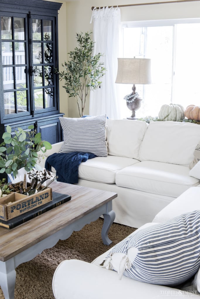 White slipcovered sectional sofa with french blue coffee table and pumpkins