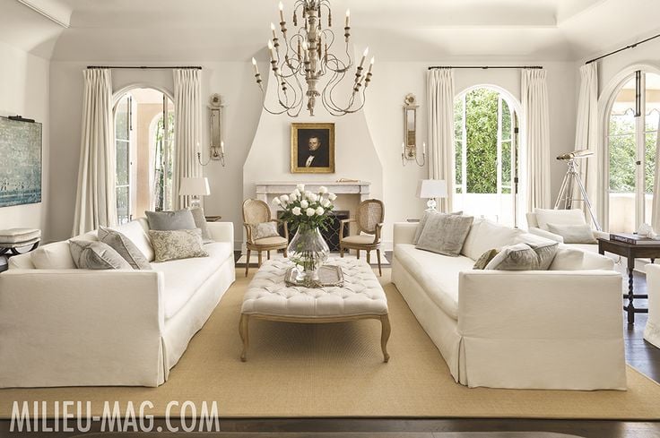 White living room with two white sofas and french tufted ottoman