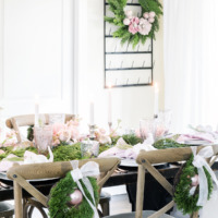 dining table with crossback chairs with pink white and green tablescape and small wreaths on backs of chairs