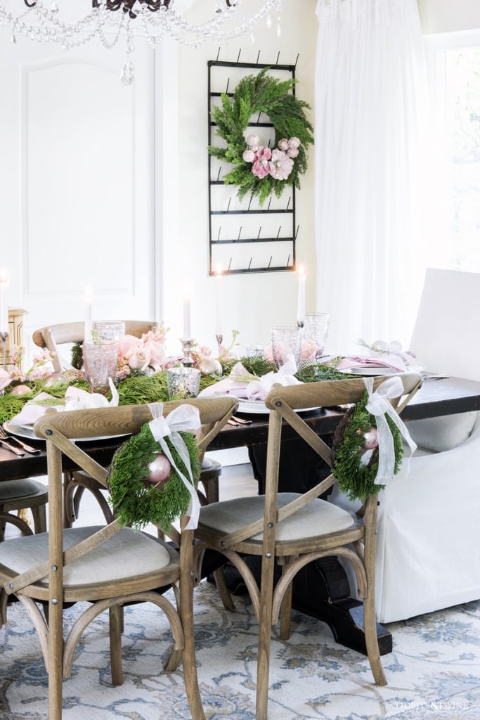 Dining room table decorated for Christmas with pink and white and cedar garland