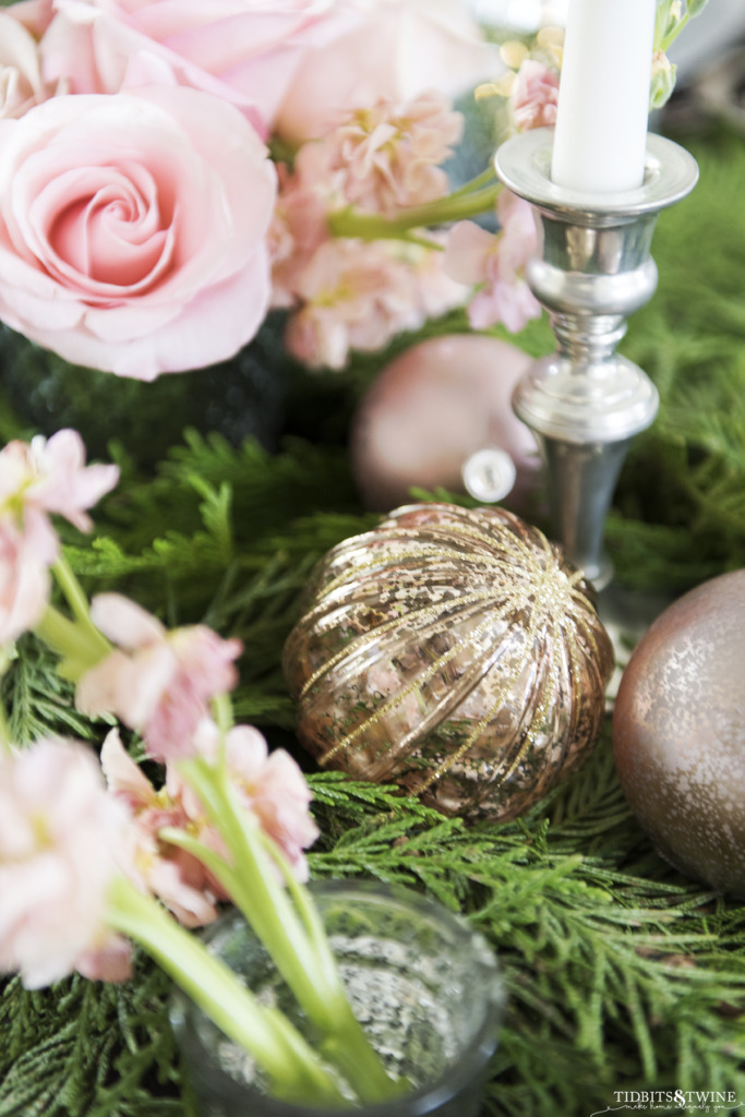 Closeup of pink ornament in cedar garland on a Christmas tablescape