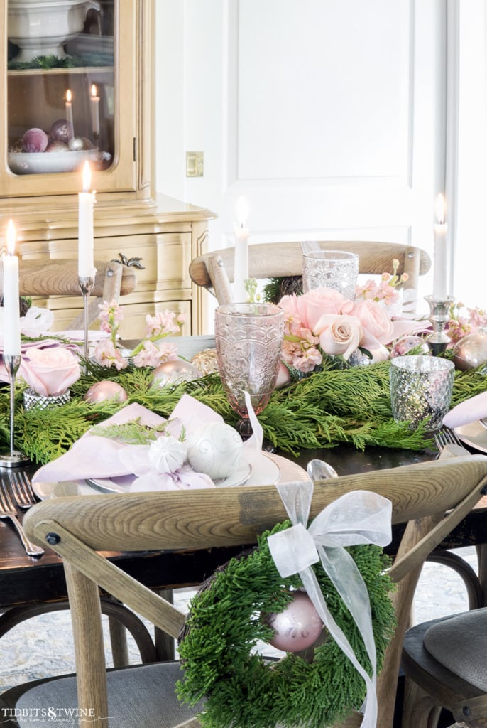 Christmas table with cedar garland and pink roses and white candles