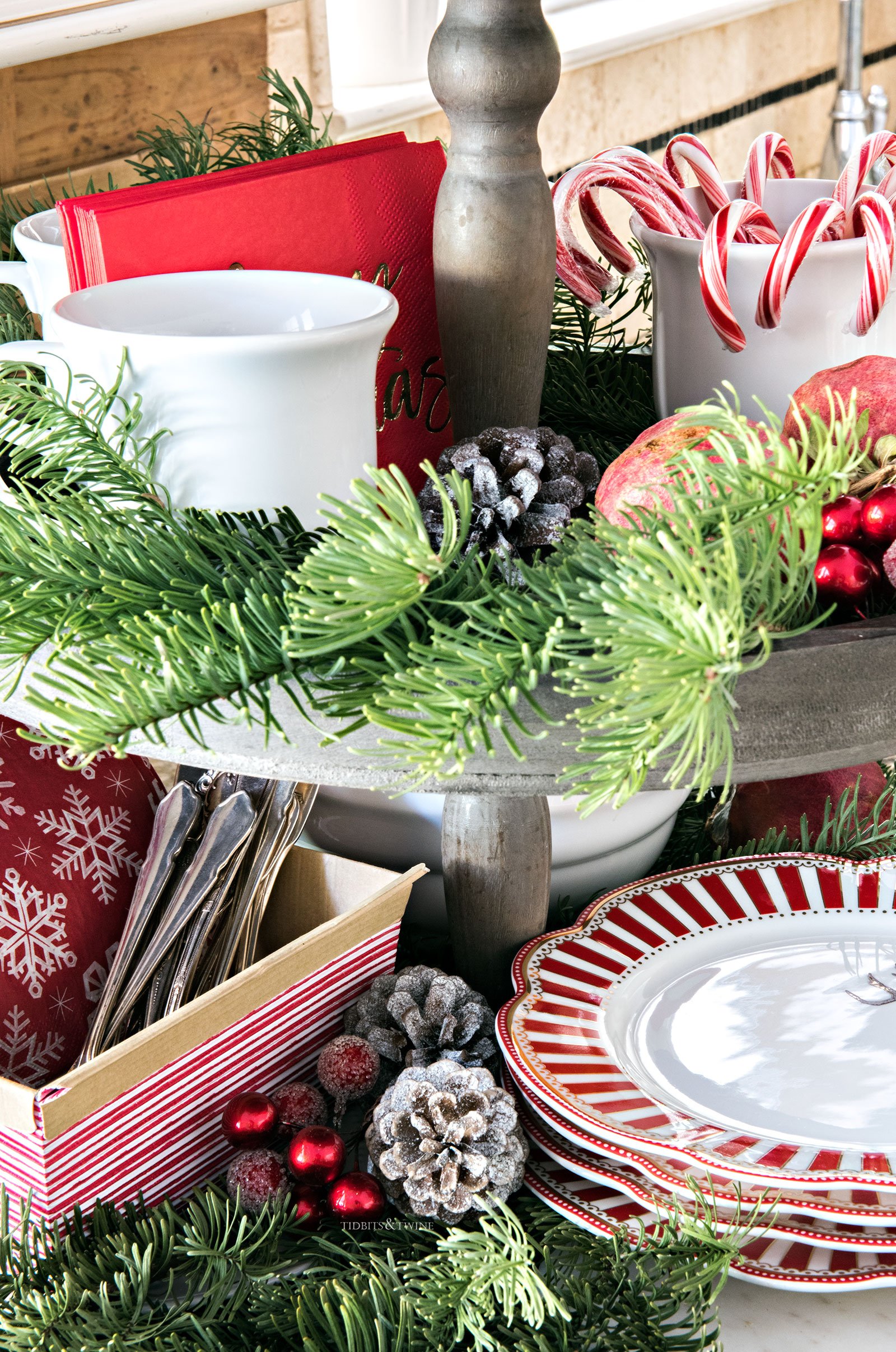 Tiered wooden tray with Christmas greens and berries white mugs with candy canes and hot chocolate