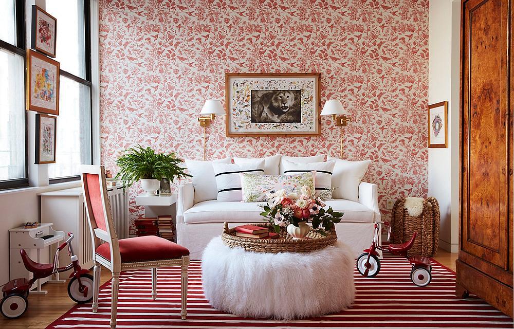 Red floral wallpaper on accent wall with red and white striped rug and white fuzzy ottoman