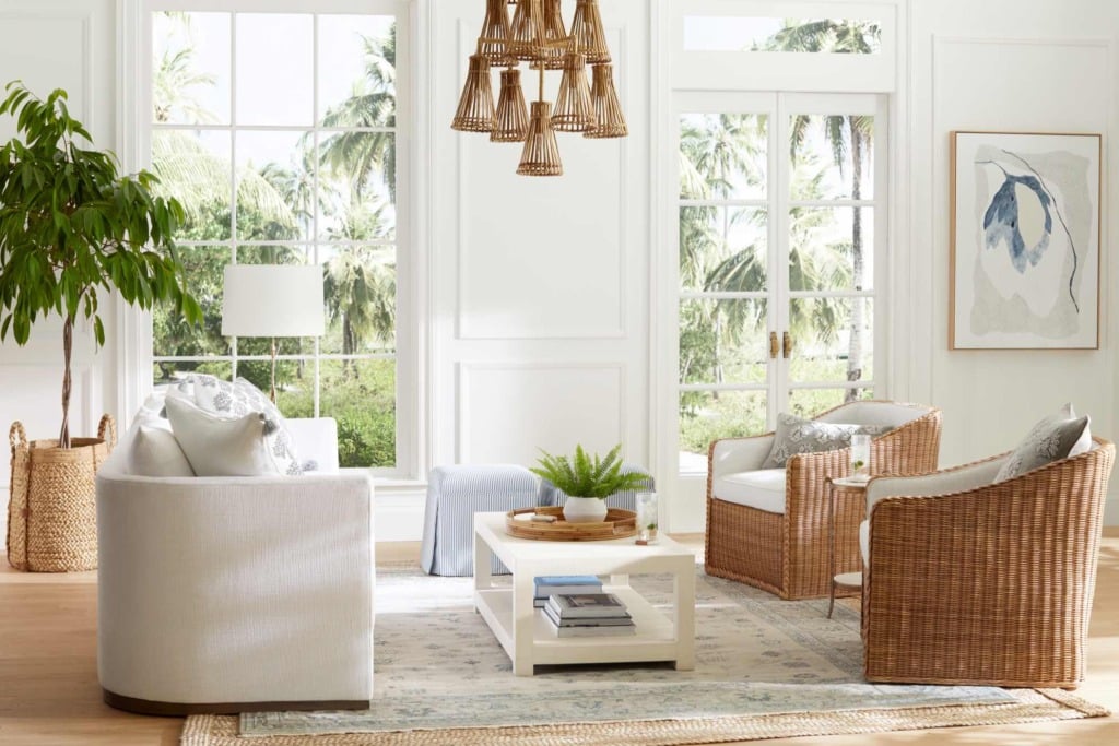 Living room with white sofa and two rattan side chairs and layered area rugs