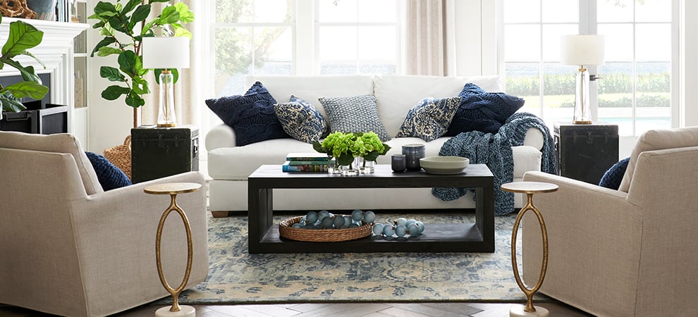 Living room with white sofa and blue throw pillows with potted fiddle leaf figs