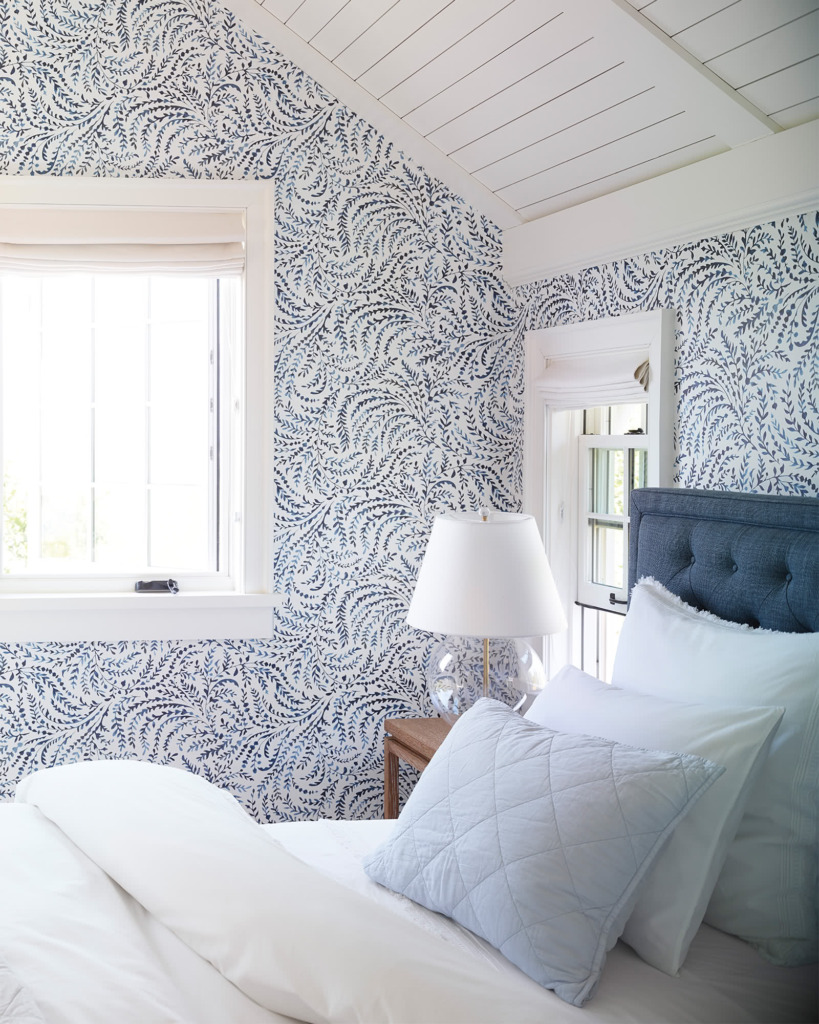 Bedroom with blue and white wallpaper white planked ceiling and blue tufted upholstered headboard