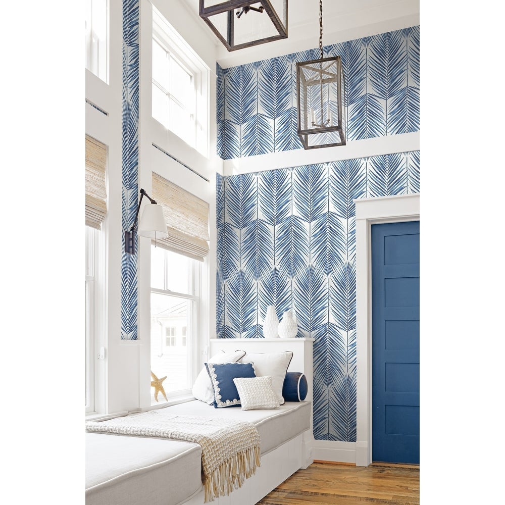 Tall entryway with blue leaf wallpaper and blue painted door and upholstered entry bench