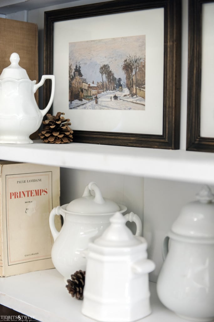 Framed winter scene artwork and books style on French bookcase