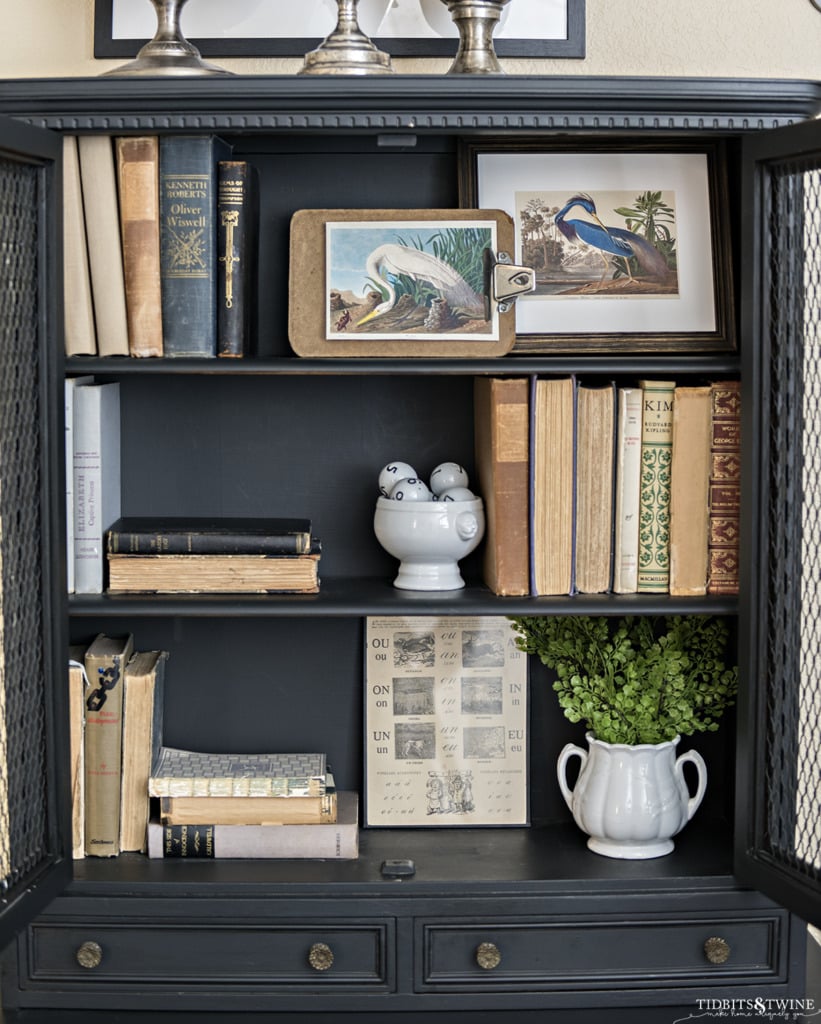 antique black cabinet with doors open showing antique books and white ironstone