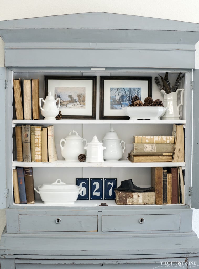 Blue French hutch styled with white ironstone antique books and free winter artwork