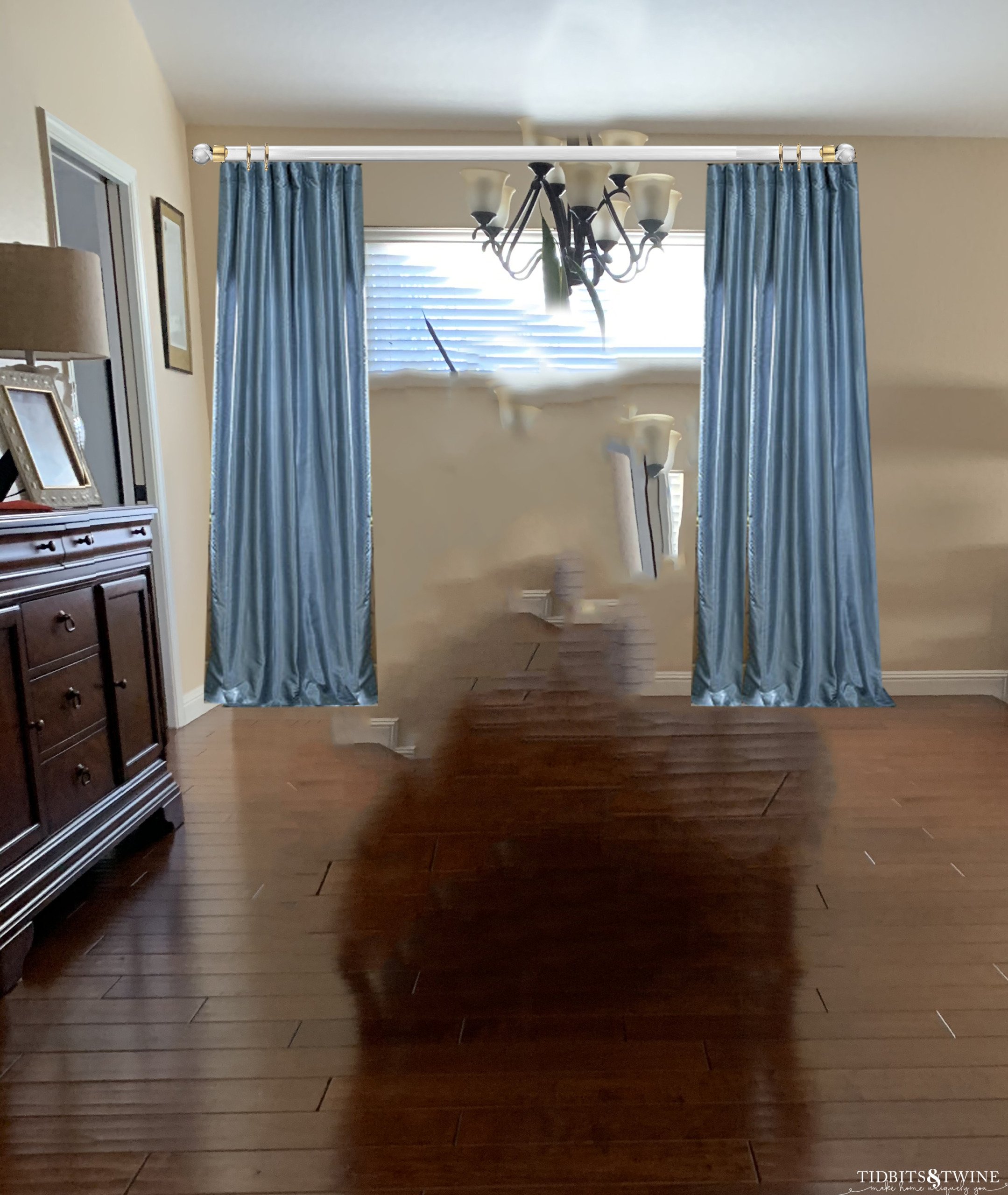 Empty dining room with blue silk curtains and acrylic gold curtain rod and wood floors