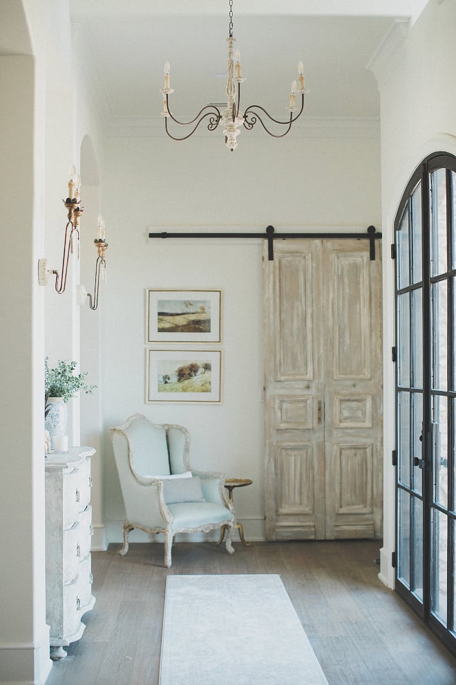 French entryway with cabinet flanked by French sconces and a light blue chair