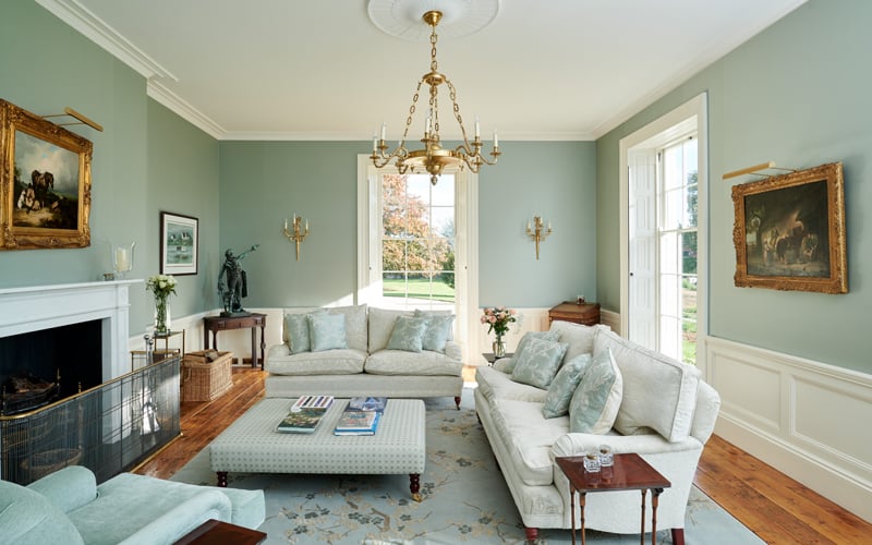 Georgian living room with light blue walls and rug white sofas and gold accents