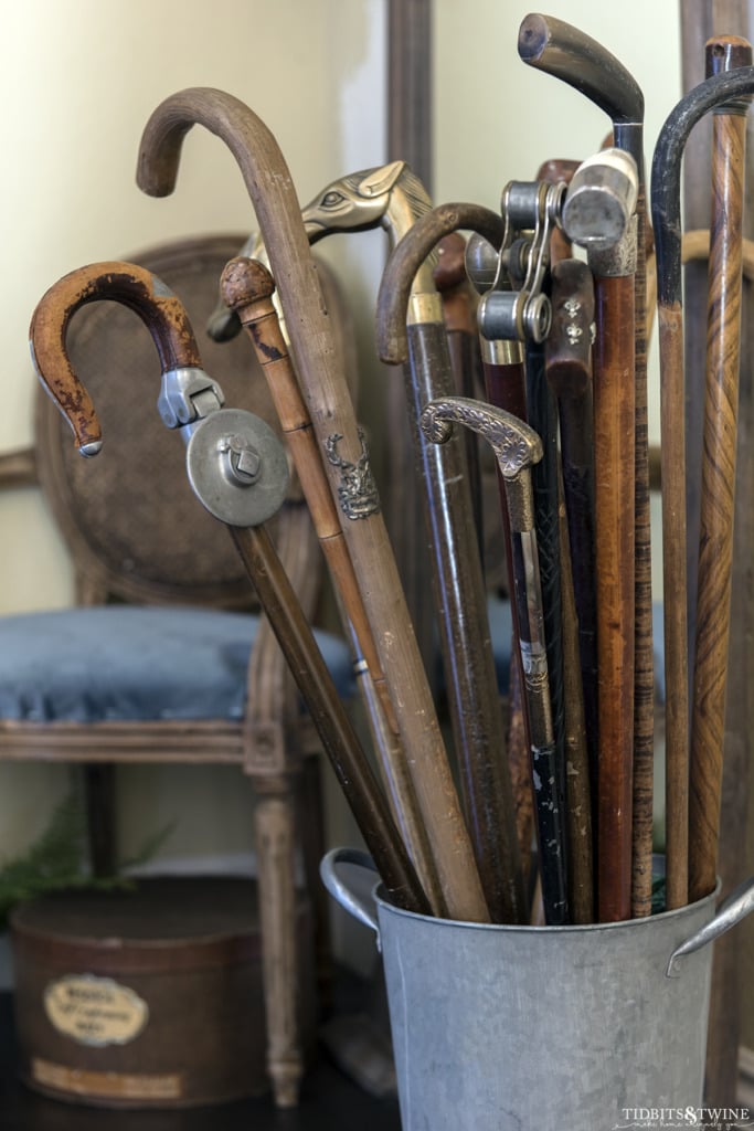 bucket full of antique canes in an entryway with blue chair in background