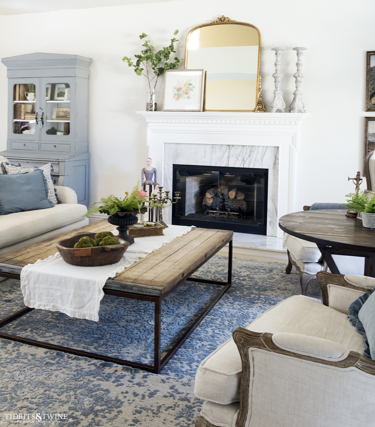 French living room in blue and white with industrial coffee table and blue hutch