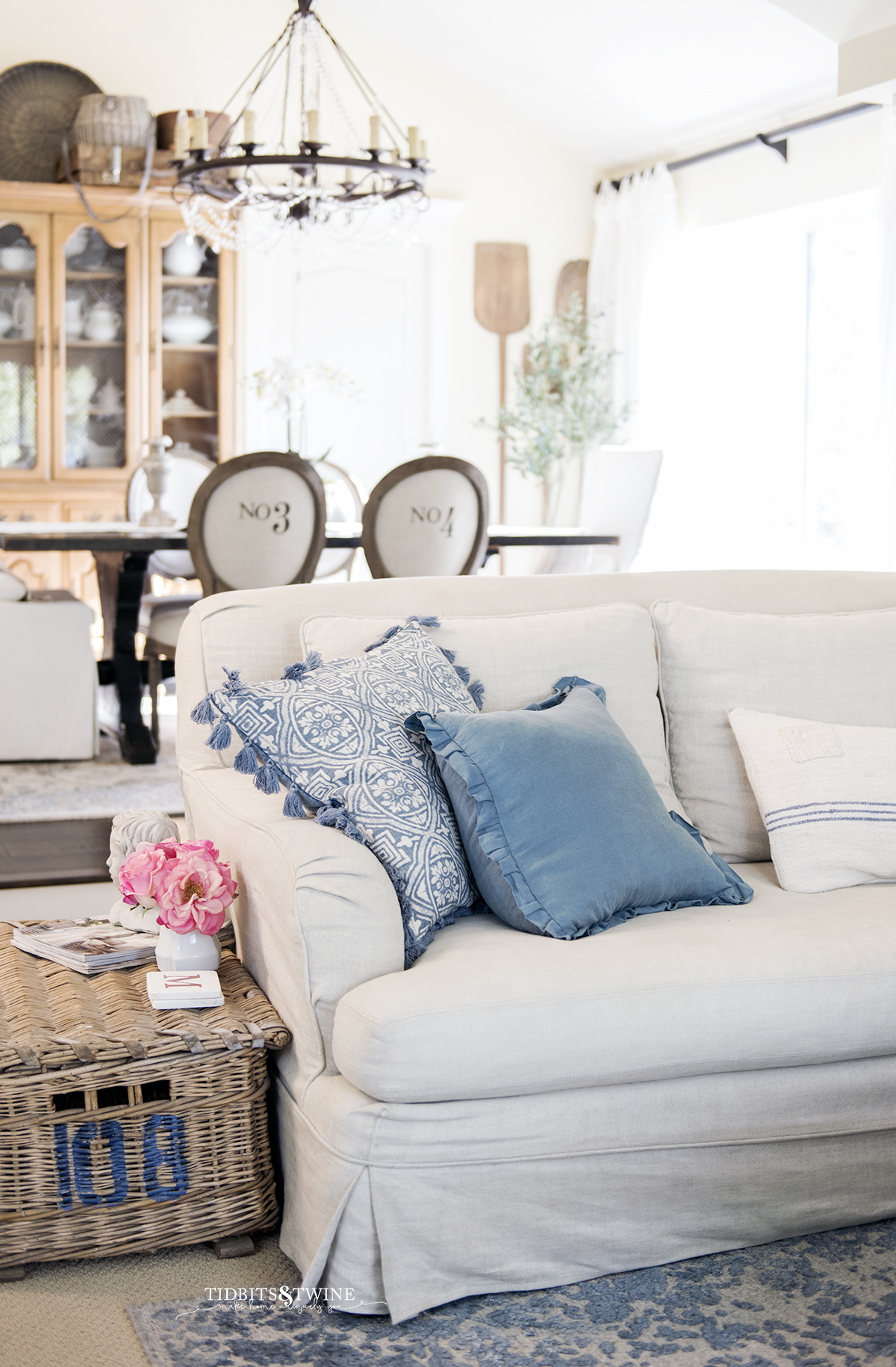 French slipcovered sofa with blue pillows and french antique basket for side table