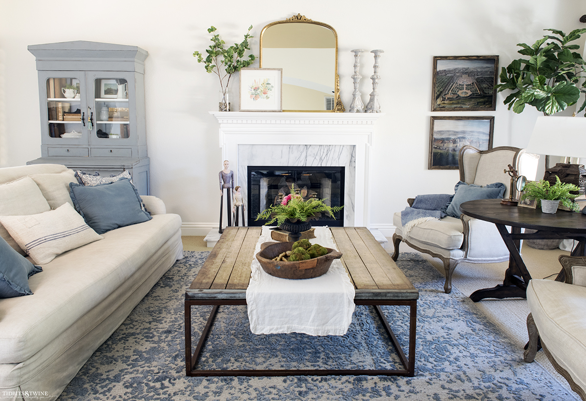 french living room with fireplace blue rug and gold mirror above mantel