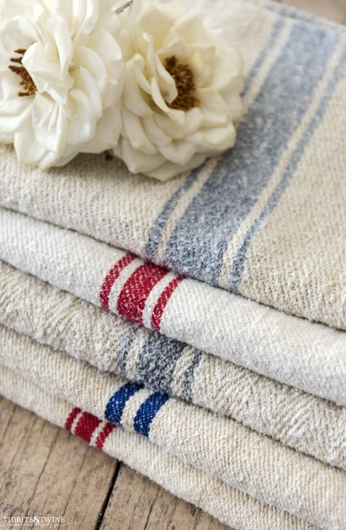 Stack of five folded vintage grain sacks with blue or red stripes in a for sale photo