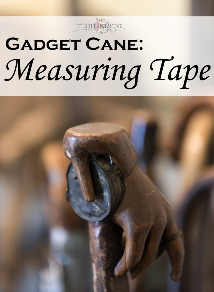 closeup of measuring tape gadget cane showing wooden hand handle holding metal tape measure