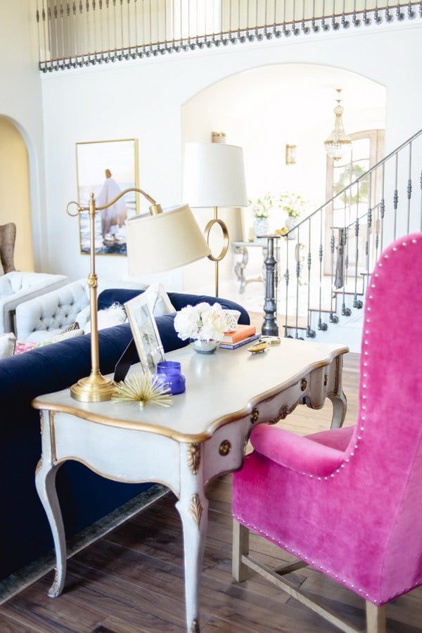 living room with french desk behind sofa with large pink desk chair