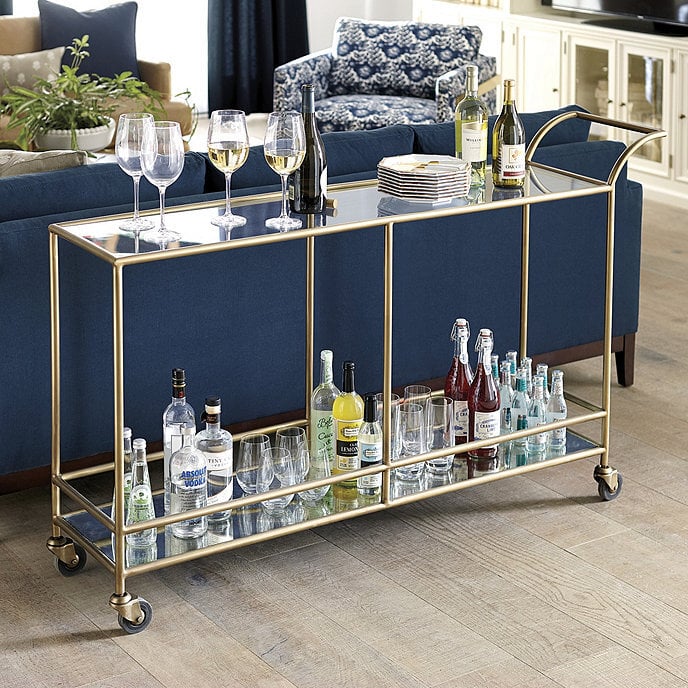 gold and glass bar cart behind a navy blue sofa in a traditional living room