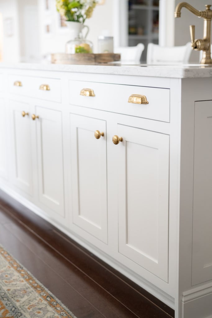 closeup of kitchen island with white inset cabinets and gold hardware