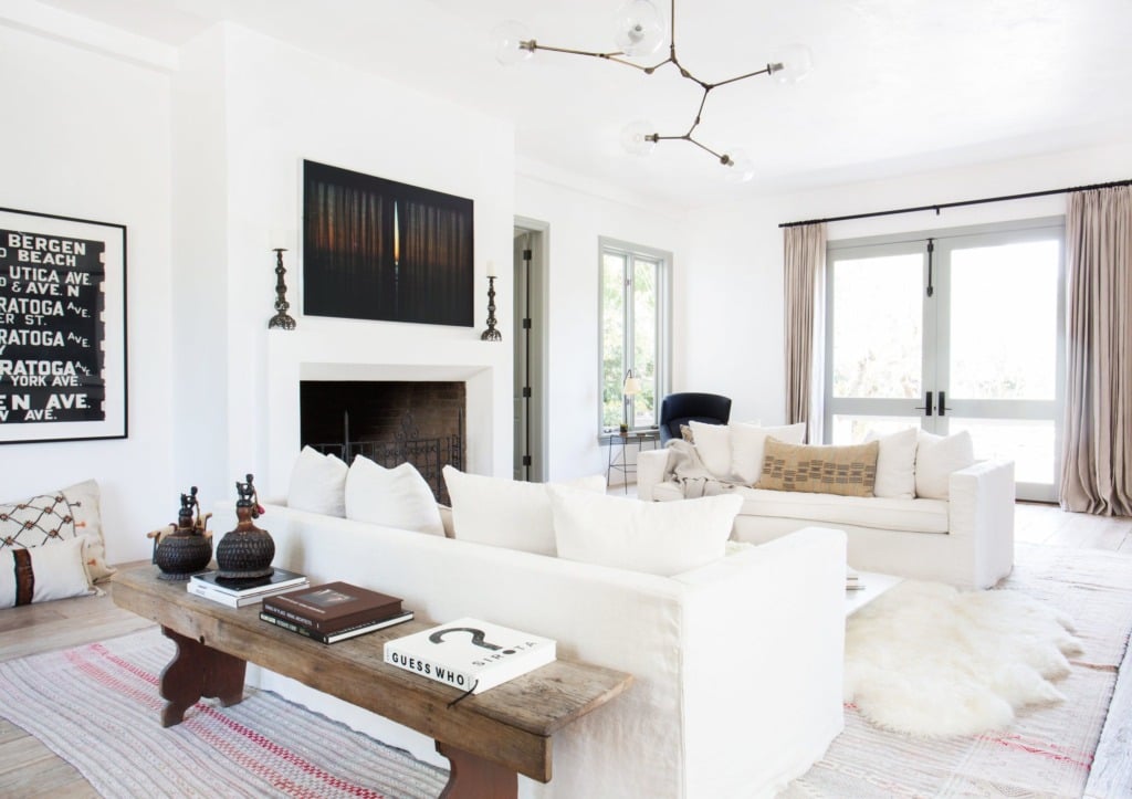 white living room with rustic wood bench behind white slipcovered sofa