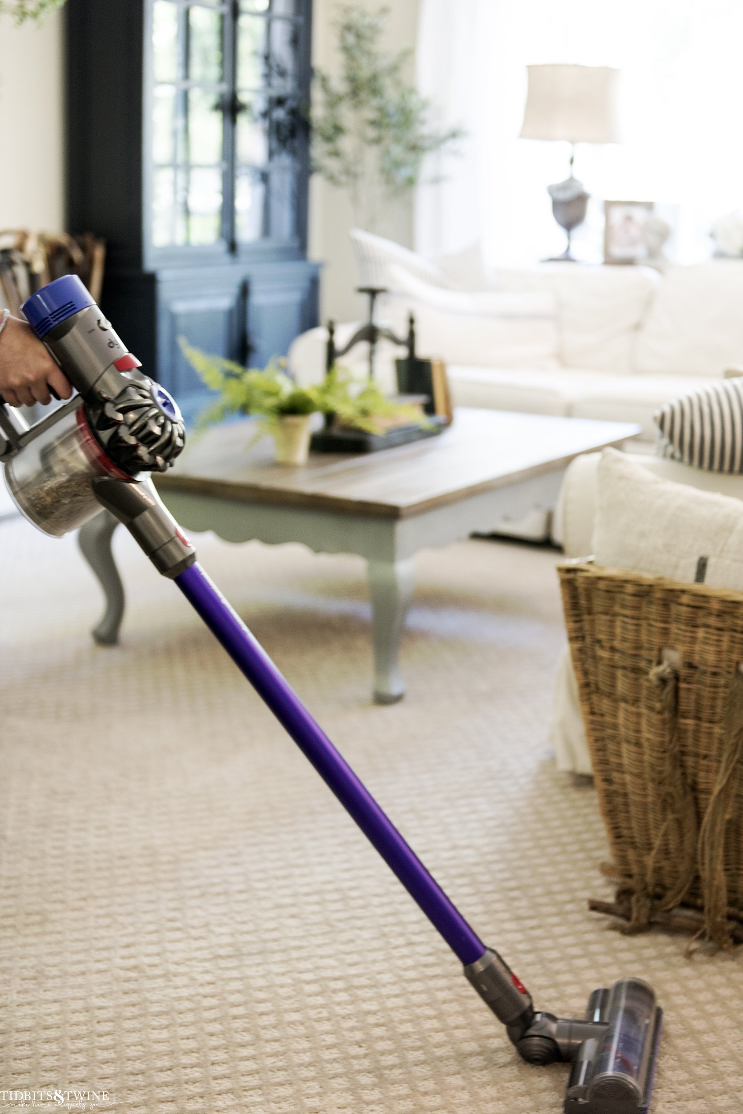 dyson cordless vacuum in french family room on diamond beige carpet with sectional in the background