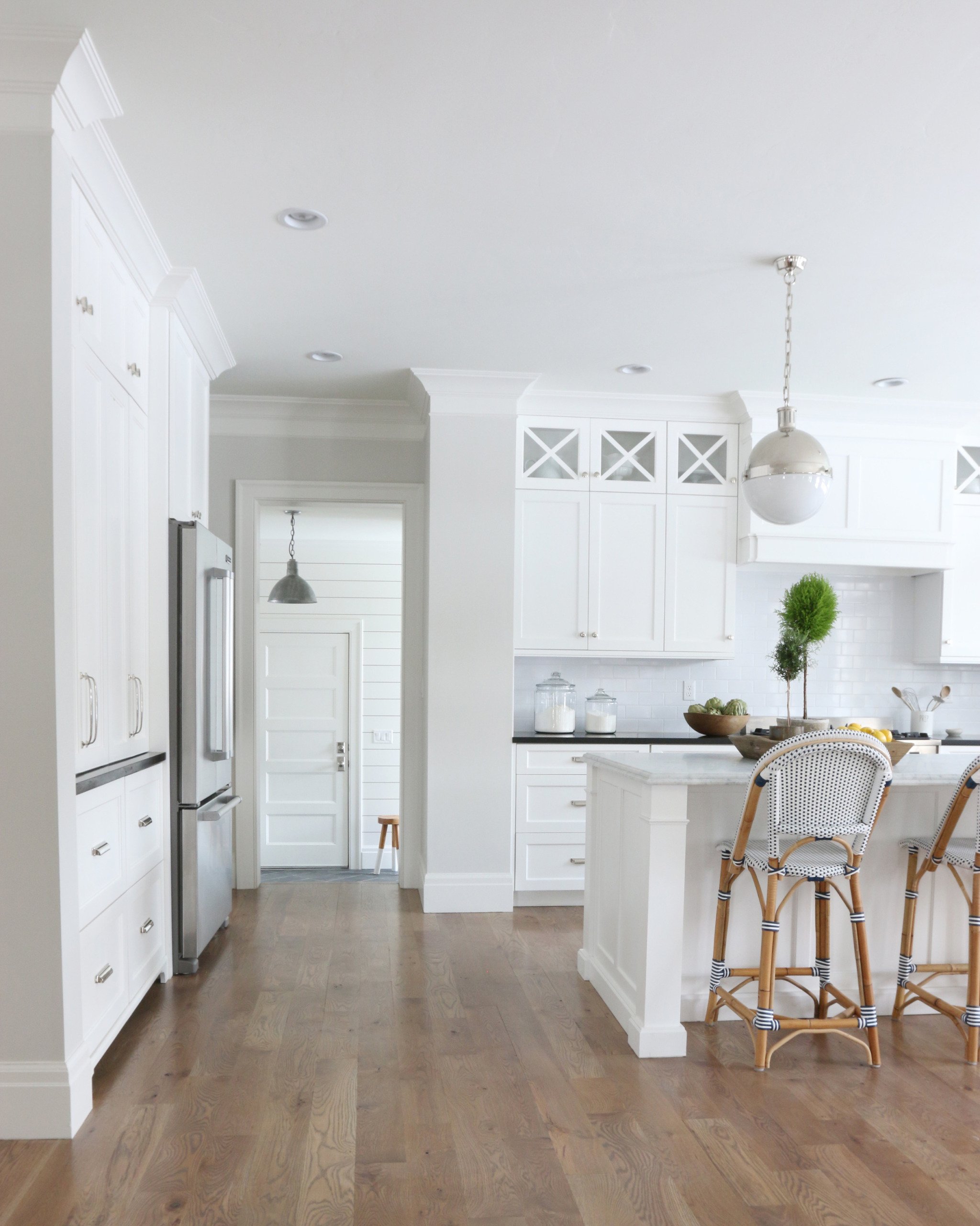 White kitchen cabinets with classic gray paint walls and serena and lily barstools and white subway tile backsplash wood floors