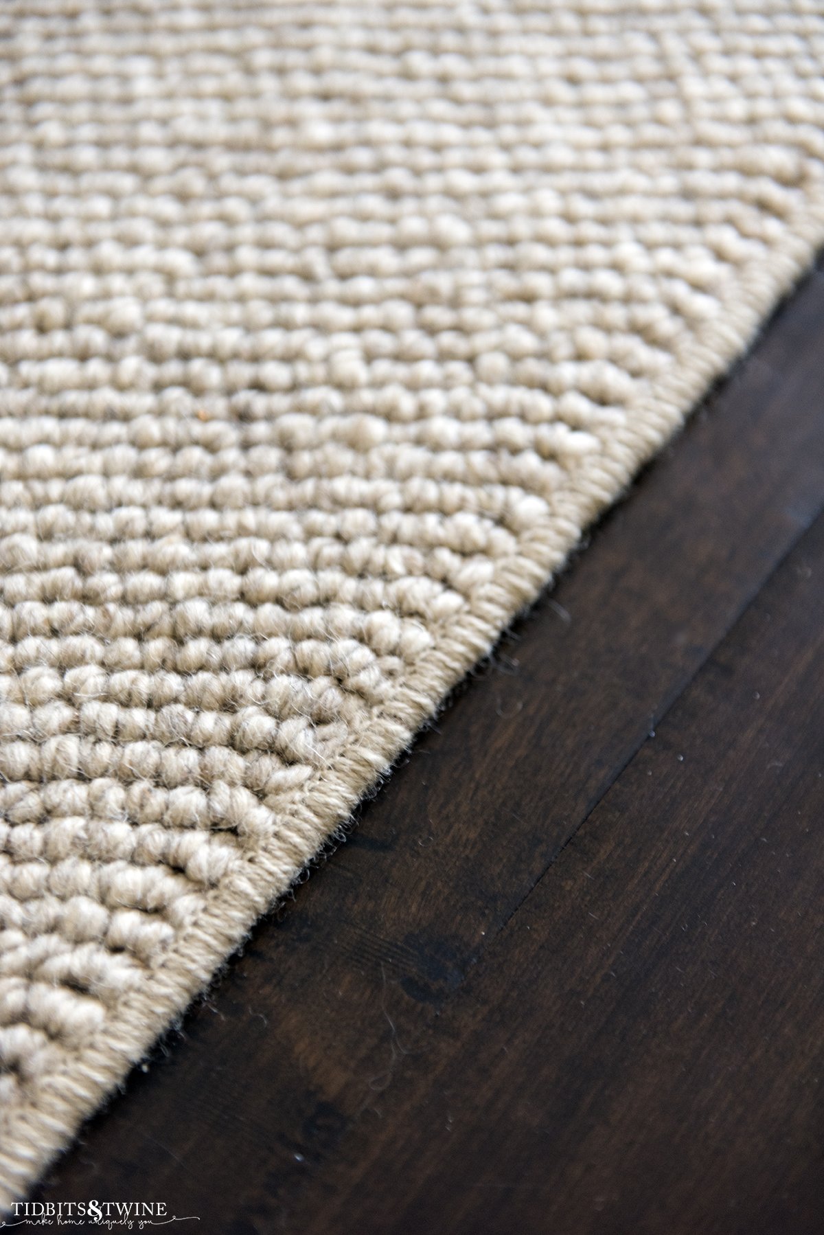 closeup of beige wool loop custom rug with standard surged edges on dark wood floor