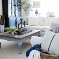 french family room with white slipcovered sectional and french style coffee table with book press on top and large black cabinet against wall