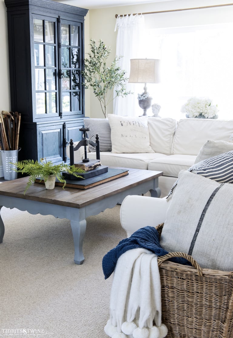 french family room with white slipcovered sectional and french style coffee table with book press on top and large black cabinet against wall