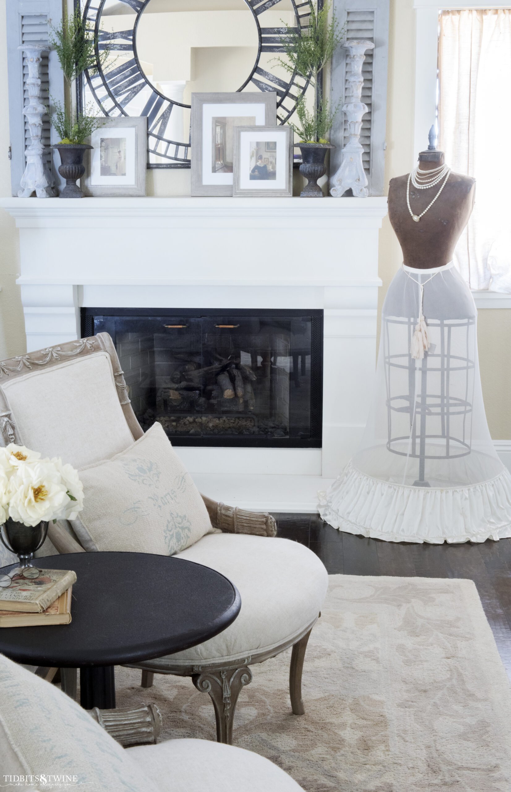 french bedroom fireplace mantel with clock mirror above and topiaries on mantel chairs at end of bed