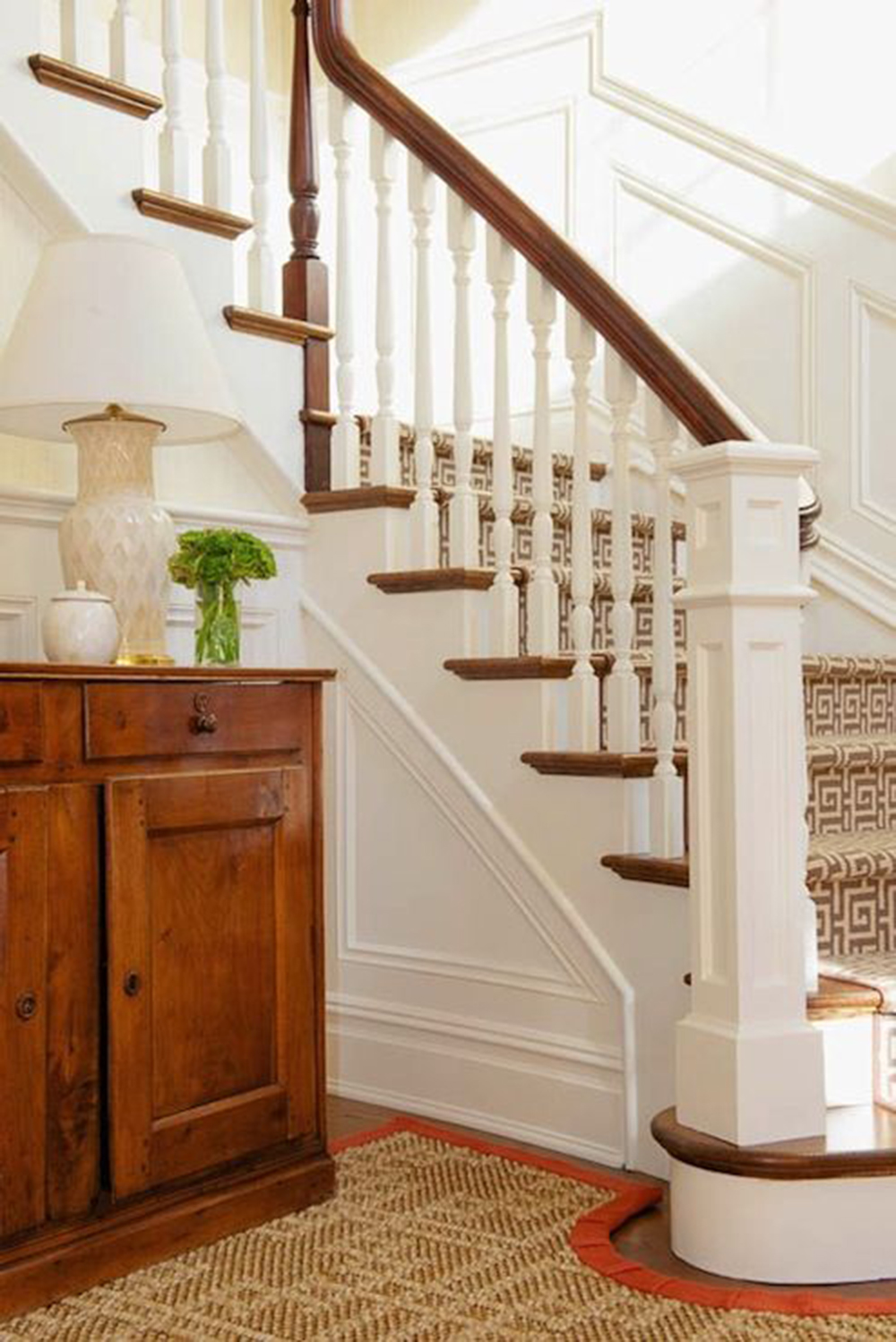 white and wood staircase with custom rug with orange binding cutout around stair post