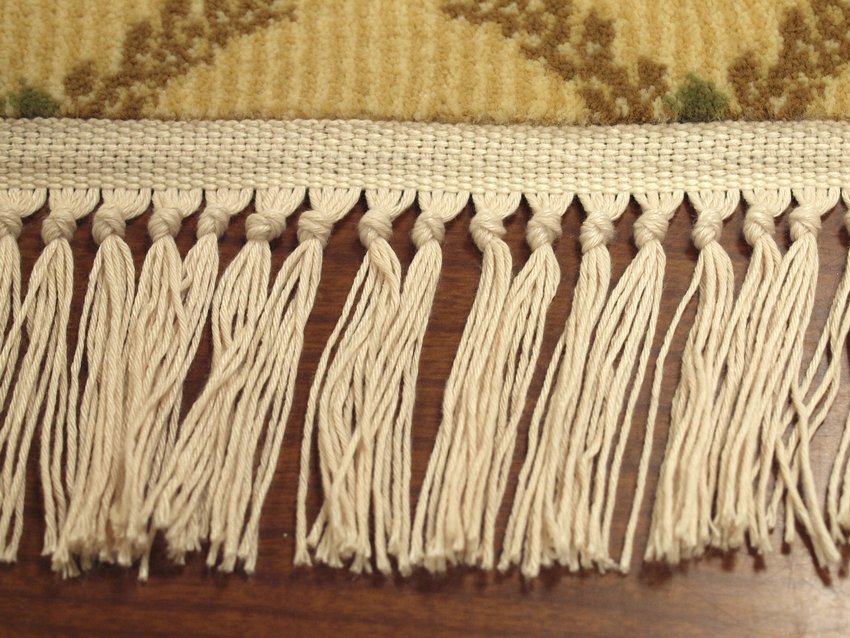 closeup of oriental custom rug with white fringe edging on wood floor
