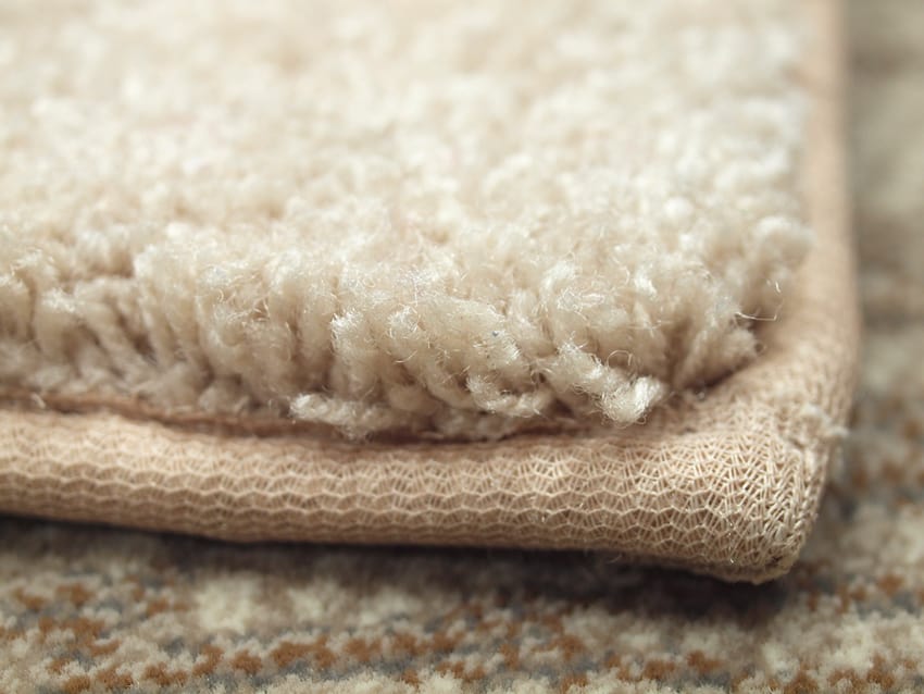 closeup of beige custom rug with standard binding tape on the edges