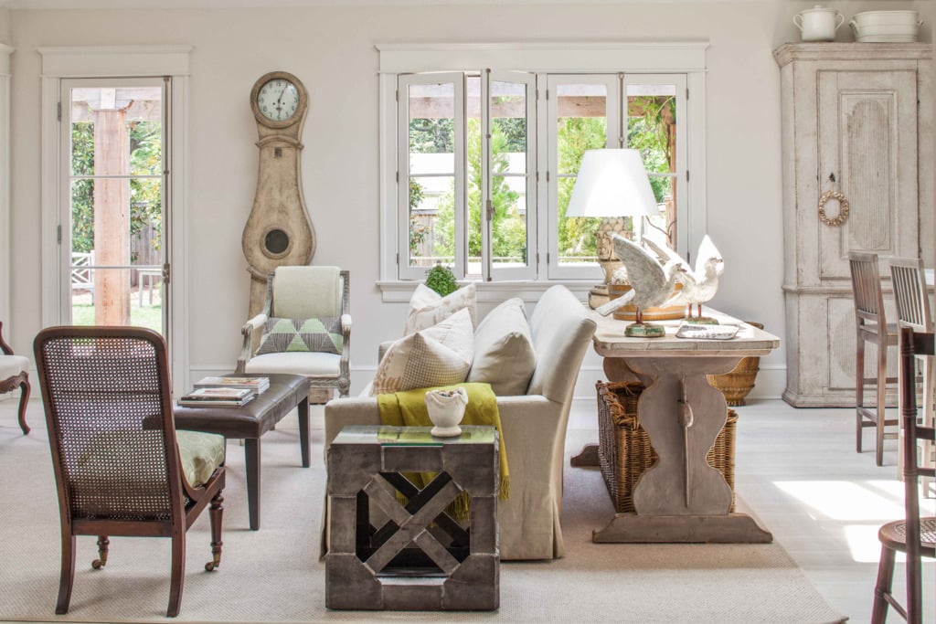 gustavian style family room with mora clock next to windows and slipcovered sofa with large table behind it