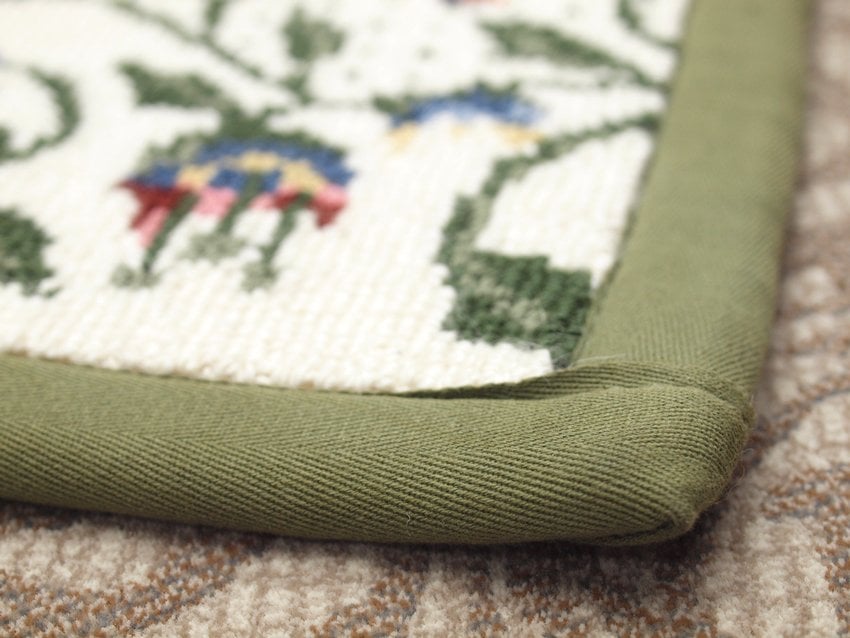 closeup of floral custom rug with wide green binding tape on the edges