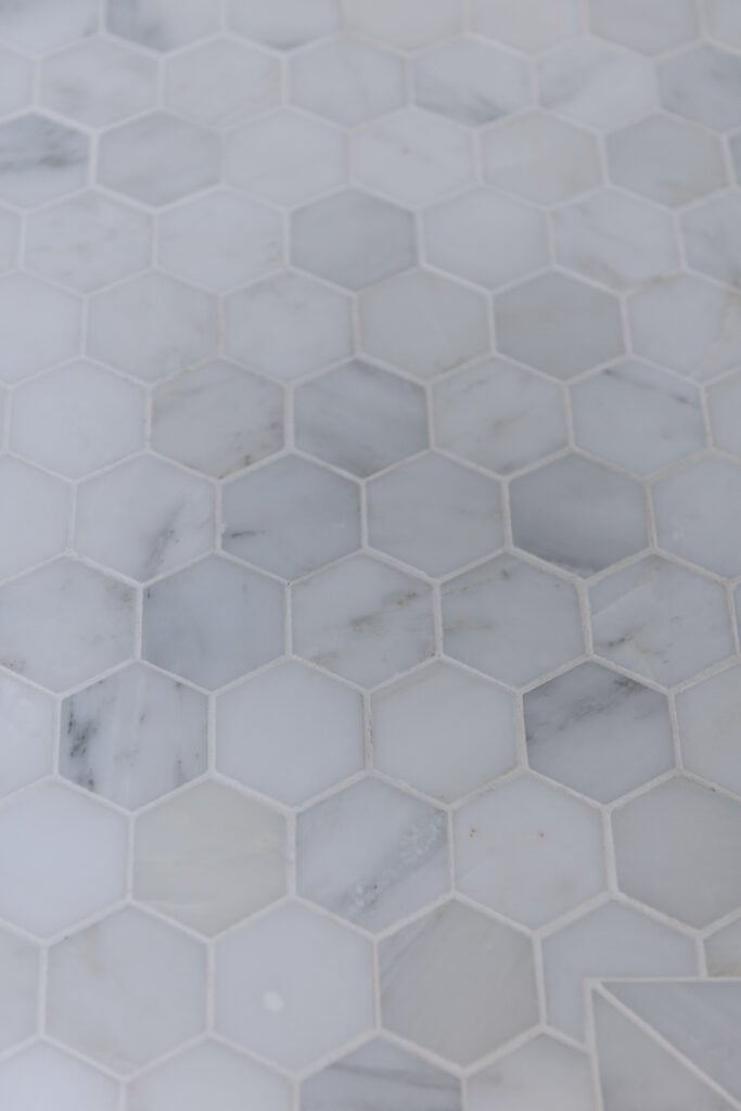 closeup of 2 inch white marble tile floor with white grout showing marble etching