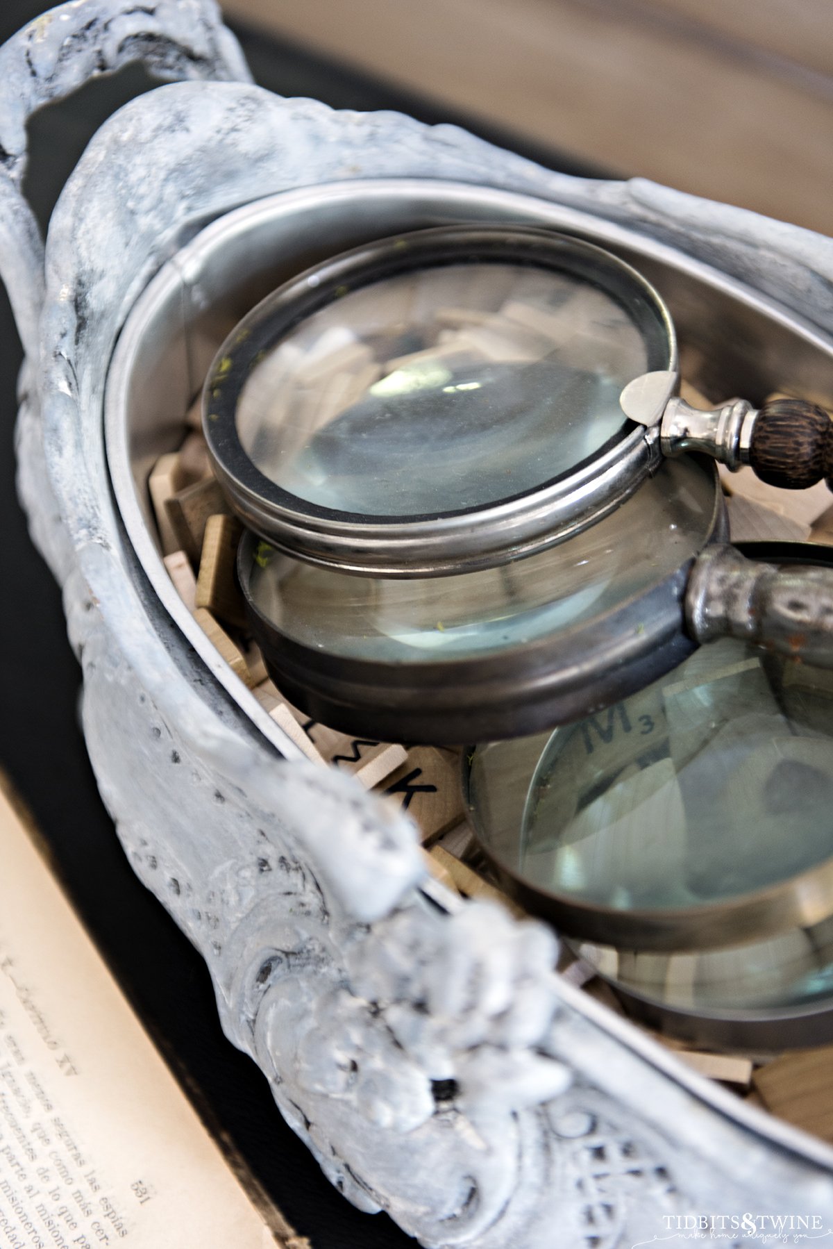 closeup of french blue jardiniere  filled with magnifying glasses and vintage scrabble tiles